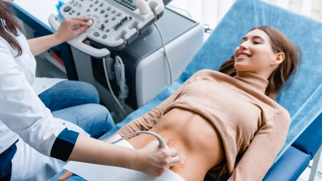 Młoda kobieta w gabinecie. Badanie USG Doppler żył miednicy.